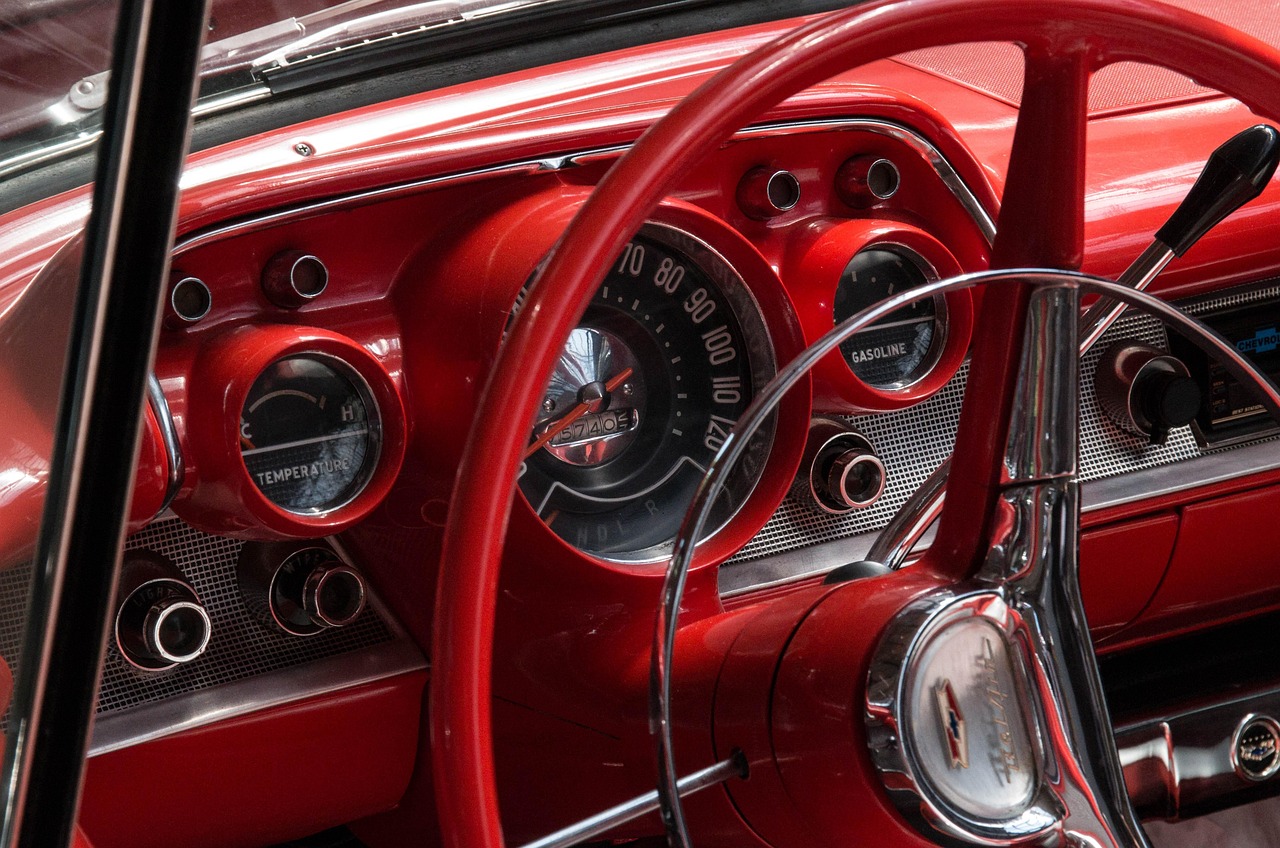 A close-up shot shows a person's hands on a car's steering wheel, with the dashboard and speedometer visible in the background.