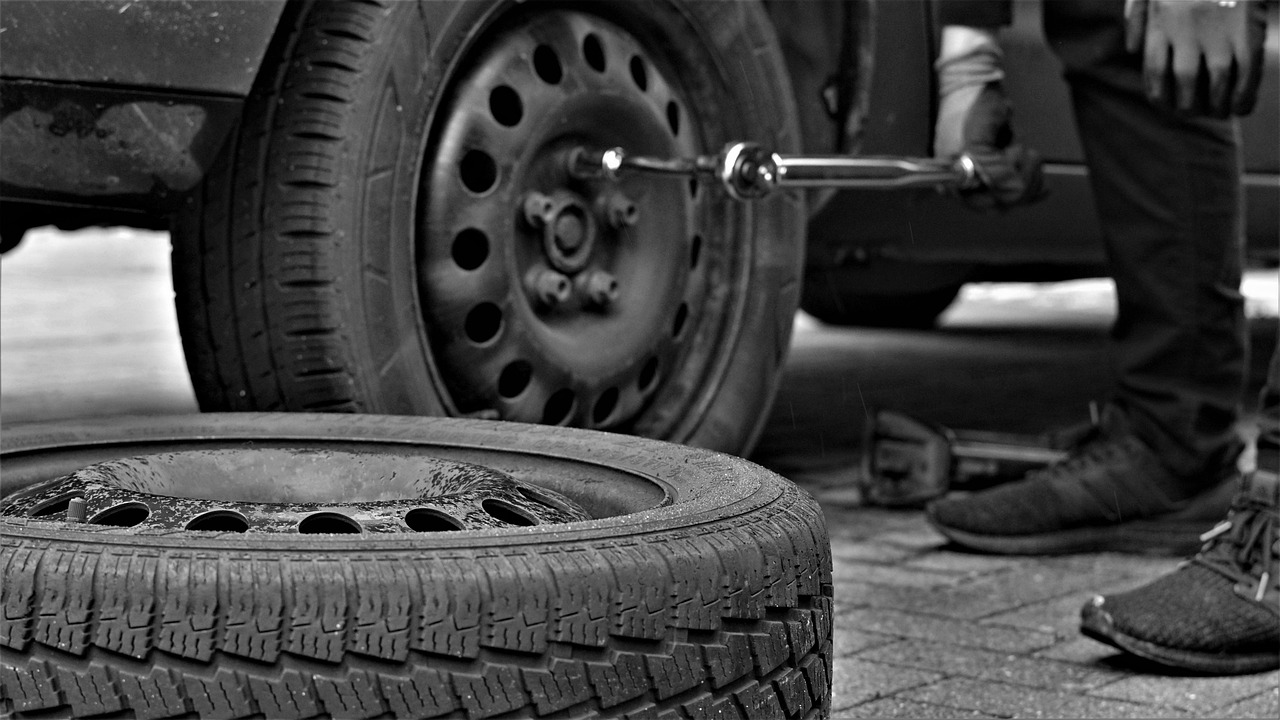 A close-up shot of a car tire with a detailed tread pattern, parked on an asphalt surface.