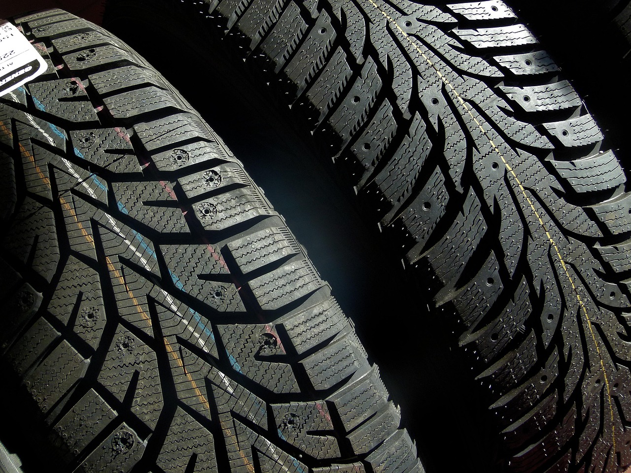 A close-up, low-angle shot shows the tread and sidewall of a black tire with a white logo, mounted on a silver wheel.