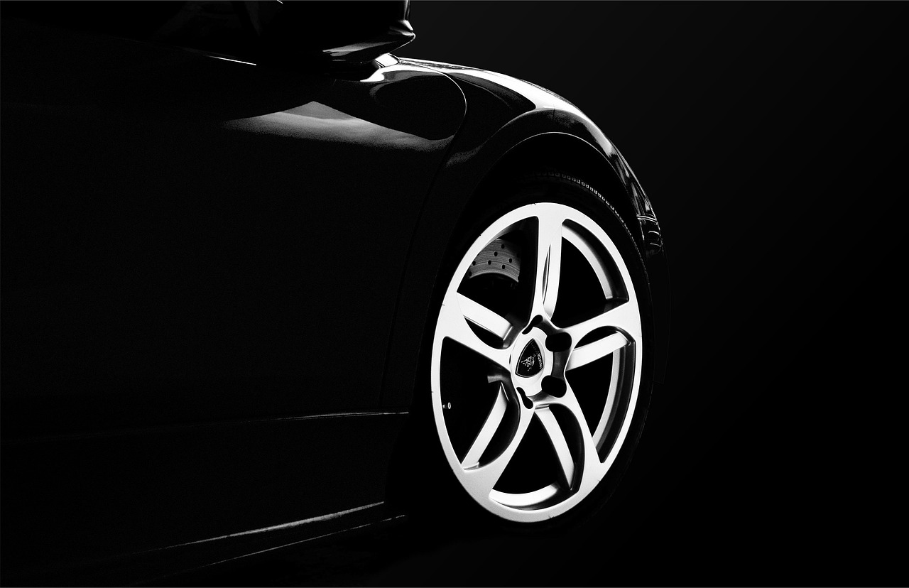 A close-up shot shows a person's hand pointing to the worn tread of a car tire, highlighting its baldness.