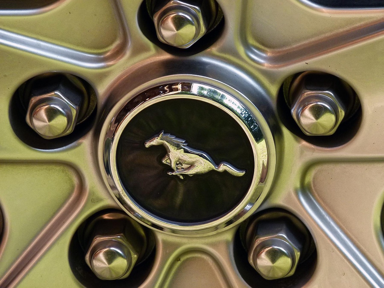 A person is using a wrench to tighten or loosen a lug nut on a car wheel, with a focus on the wheel and the tool.