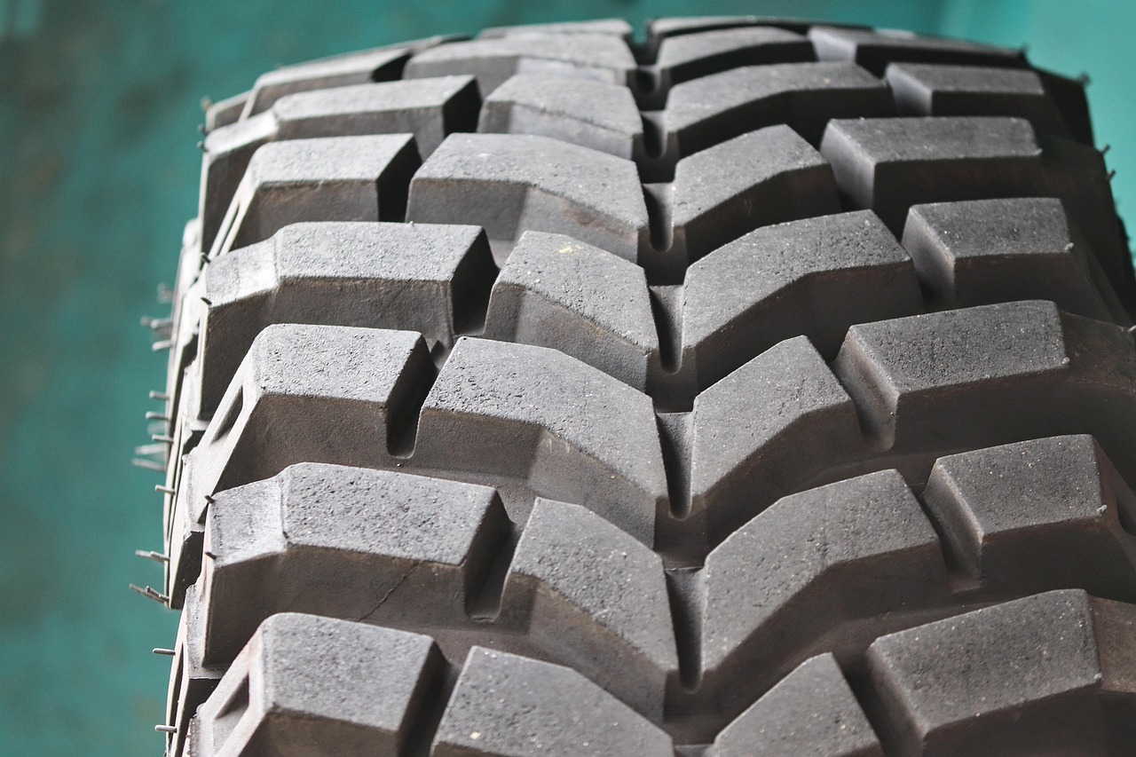 A close-up shot shows the tread and sidewall of a car tire, with visible branding and text on the rubber.
