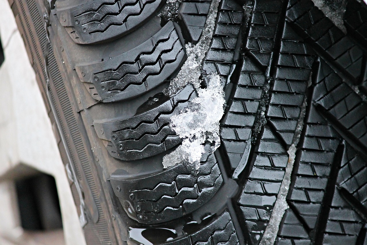 A close-up shot shows the tread pattern of a car tire, highlighting its grooves and sipes.