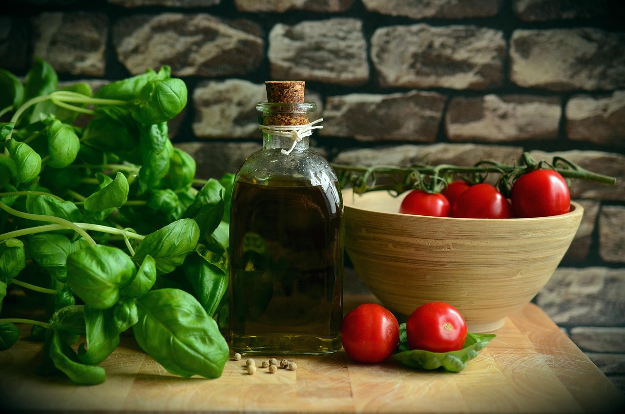 A close-up shot shows fresh green basil leaves with water droplets on them, some still attached to a stem.