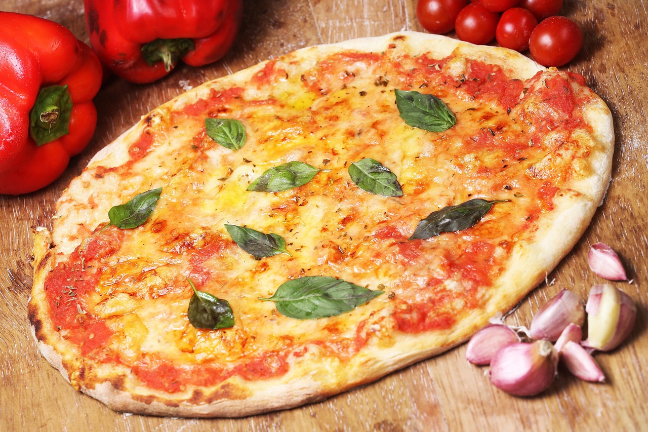 A close-up shot shows a slice of pizza being pulled from a whole pizza, with visible melted cheese, tomato sauce, and basil leaves.