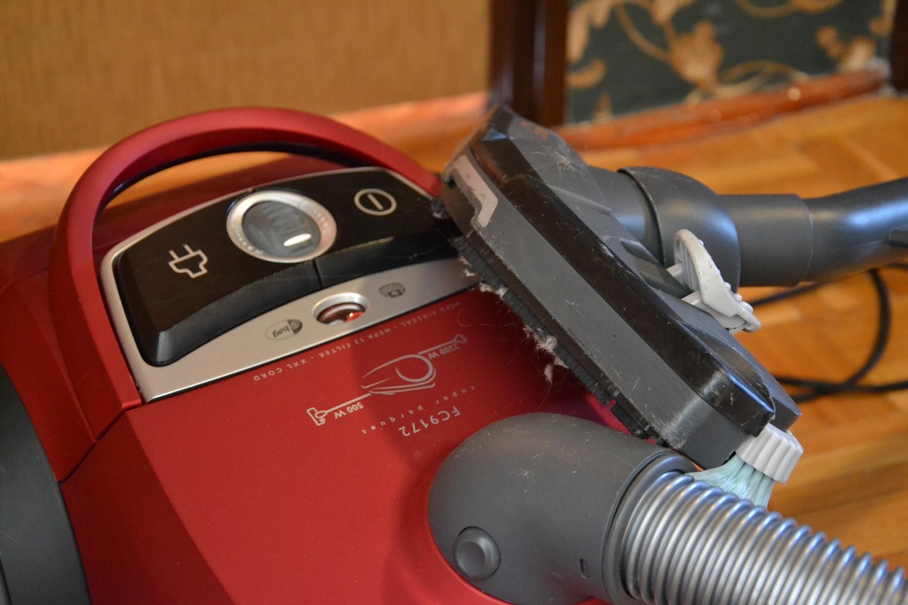 A person is using a vacuum cleaner to clean a light-colored, shaggy rug or carpet.